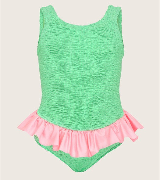 Green swimsuit with pink ruffle on a beige background